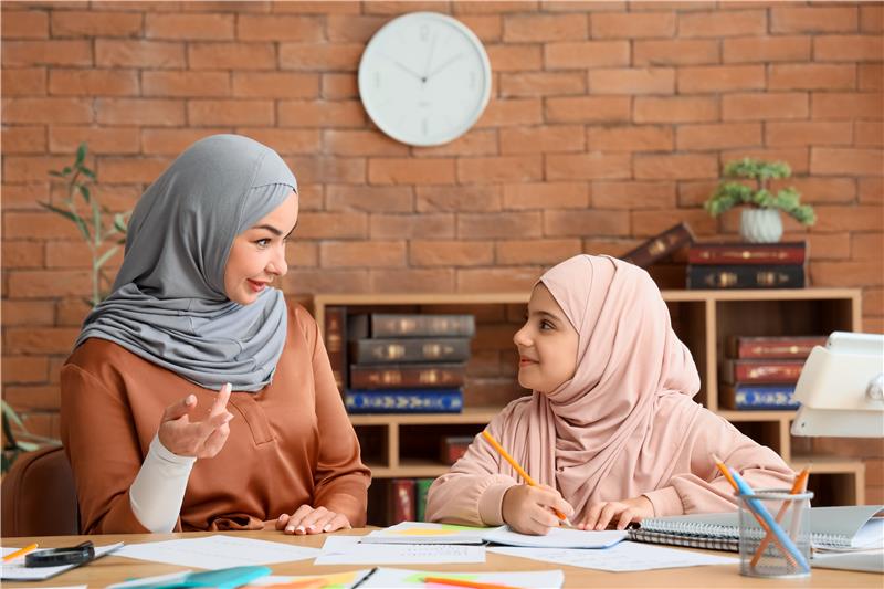 Muslim parent guiding her daughter’s learning with care, reflecting faith-based parenting in the digital age.